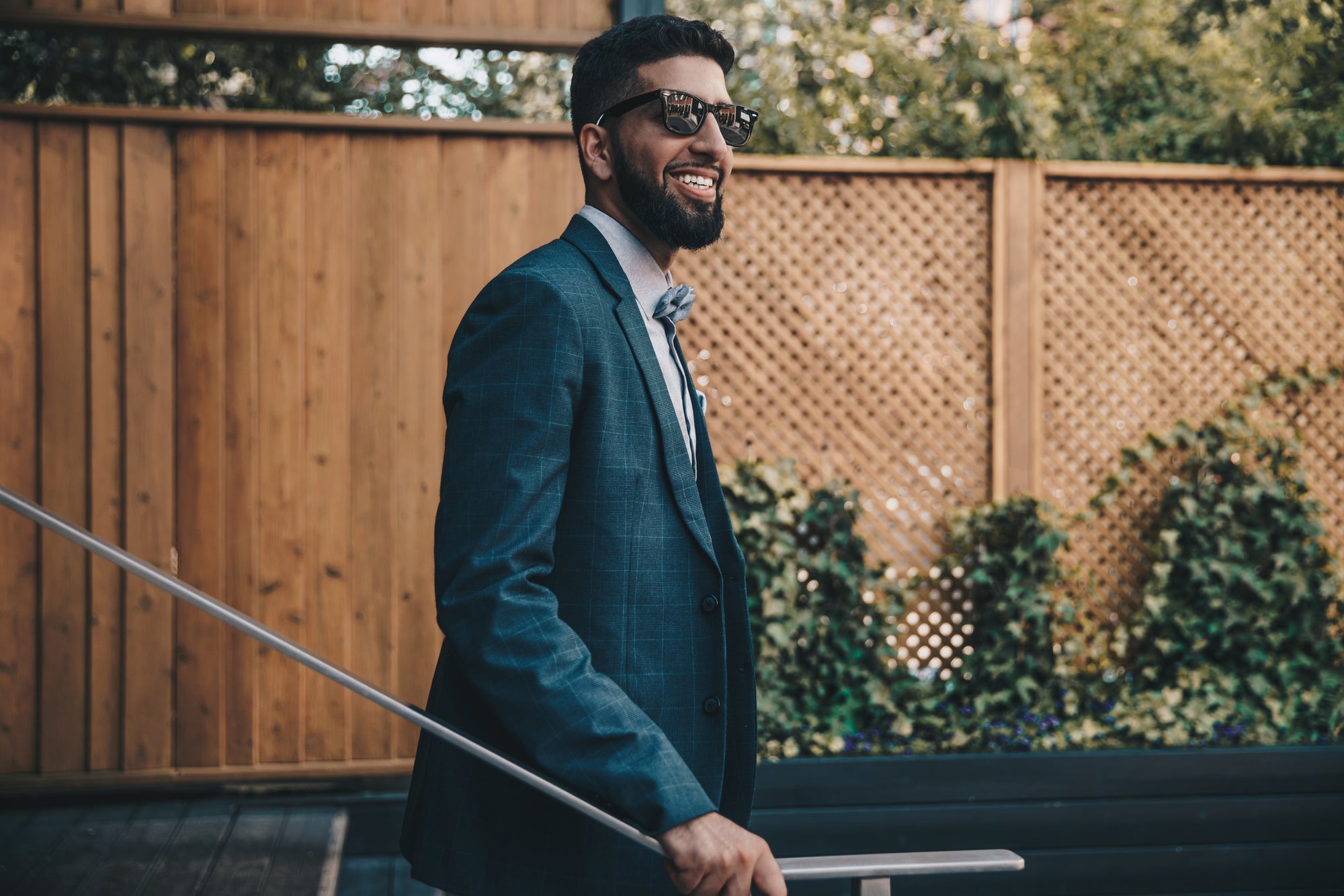 man in suit and sunglasses grinning while walking outside