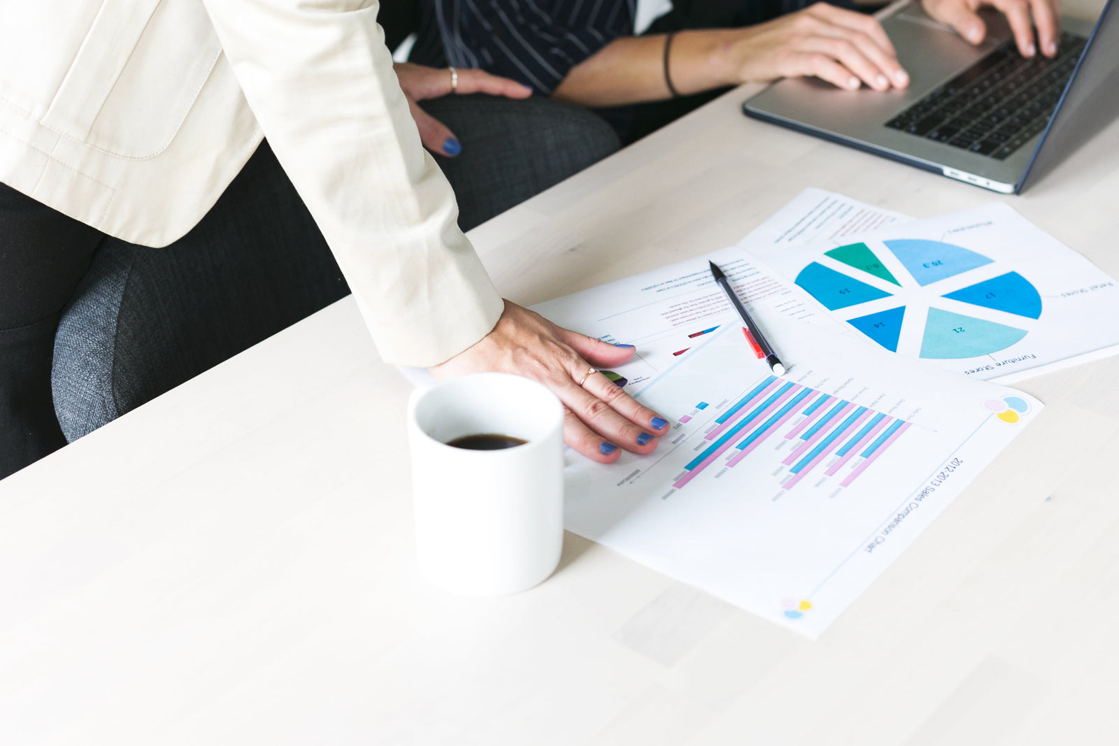 colorful graphs and peoples hands working on a desk 